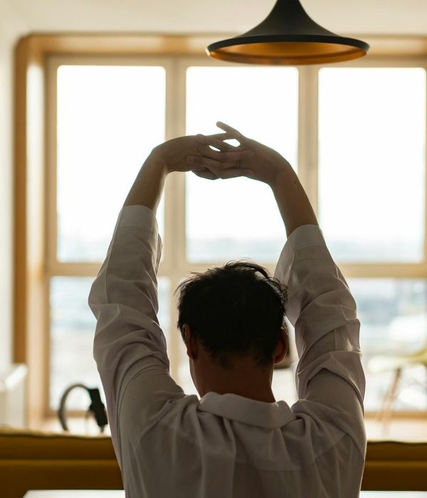 Man stretching thoughtfully in a well-lit, spacious room.
